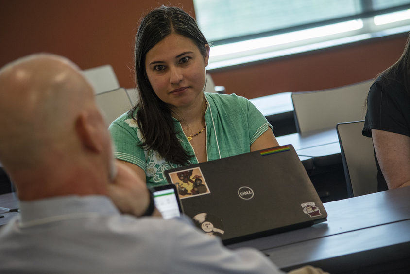 Person seated at conference table talking to others