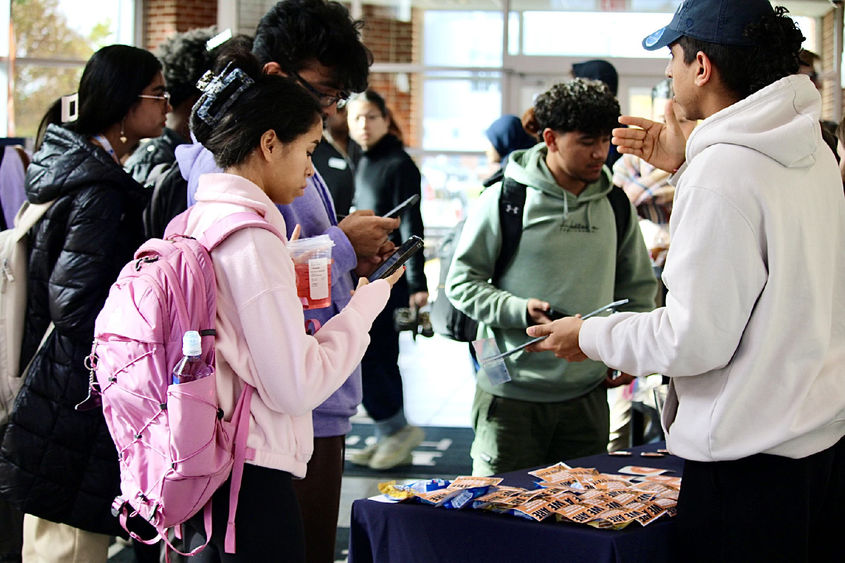 Students approach an information table during a first-gen student event in Olmsted Building atrium