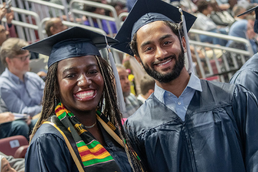 two students posing in caps and gowns at commencement