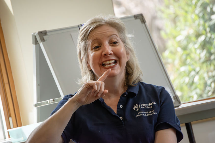 Heidi Haas points to her lips as she demonstrates how to make a sound
