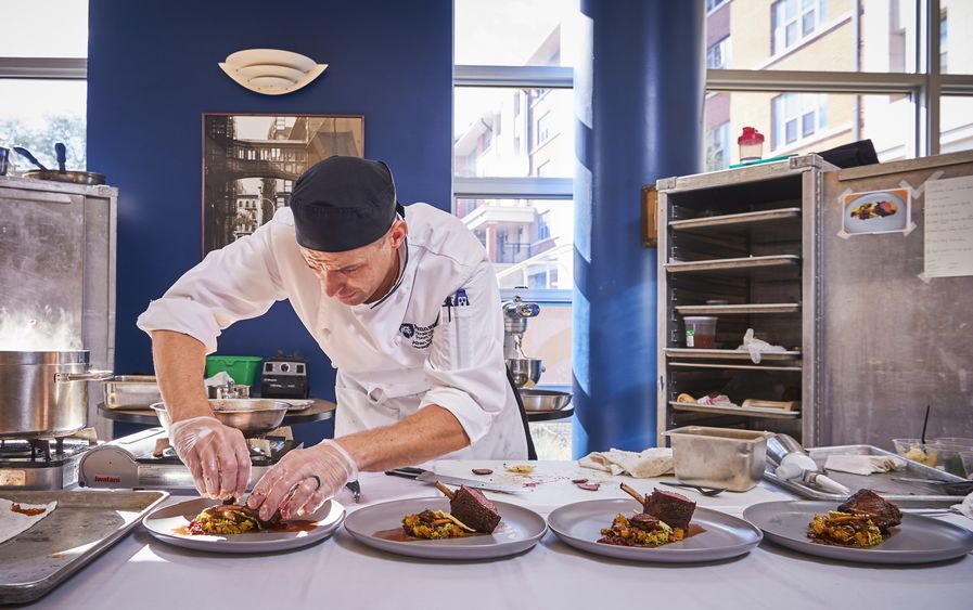 A chef works on plating food