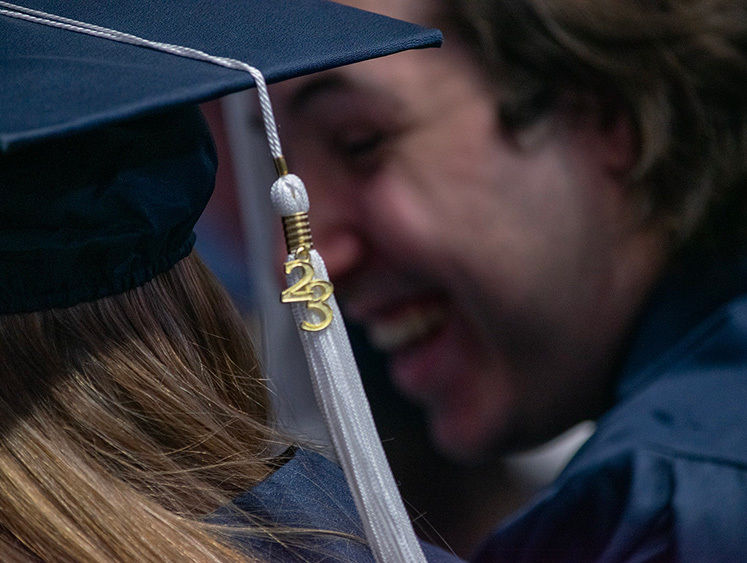 A class of 23 tassel dangles in front of smiling graduate faces