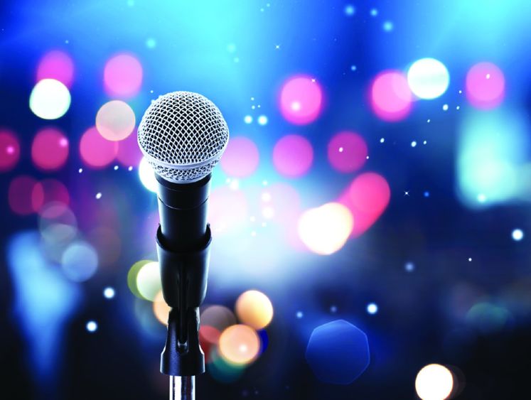 Image of microphone on stand with stage lights in the distance