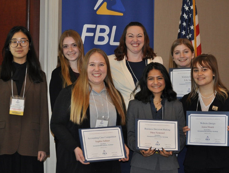 Group photo of seven people. Four students hold certificates.