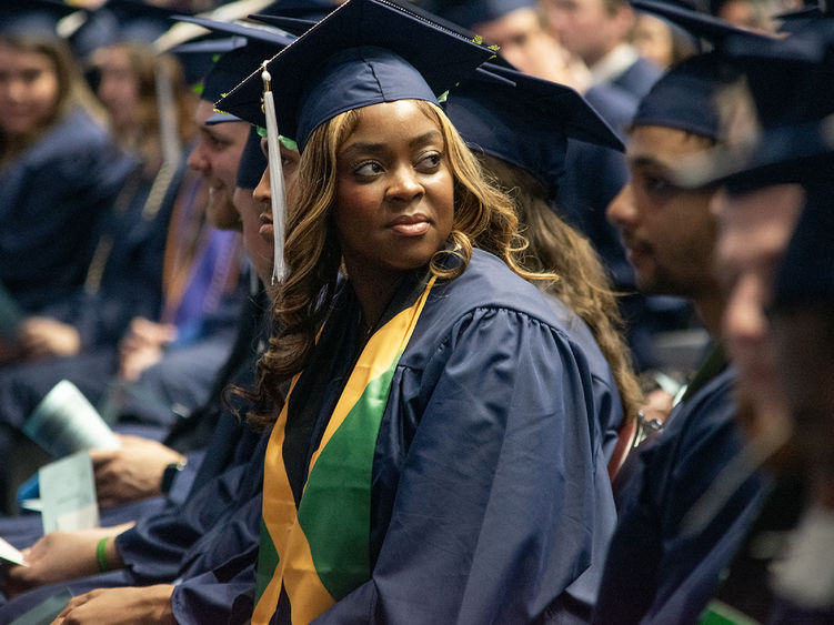 A graduate looks into the crowd during commencement