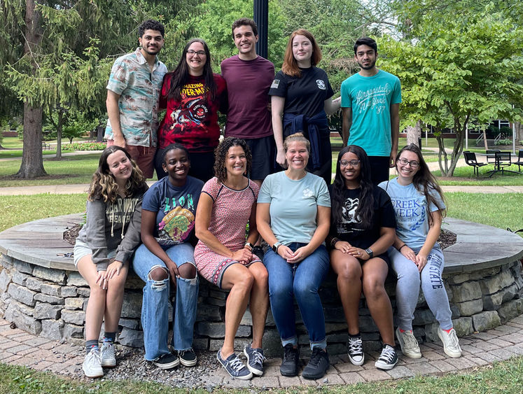 A photo of a group of 11 Penn State Harrisburg students and staffers, sitting on a stone wall outdoors