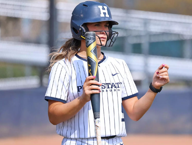 Madelyn Lehigh in a softball uniform holding a bat