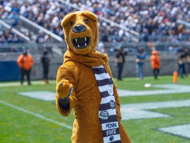 The Nittany Lion points to the camera while standing on the football field