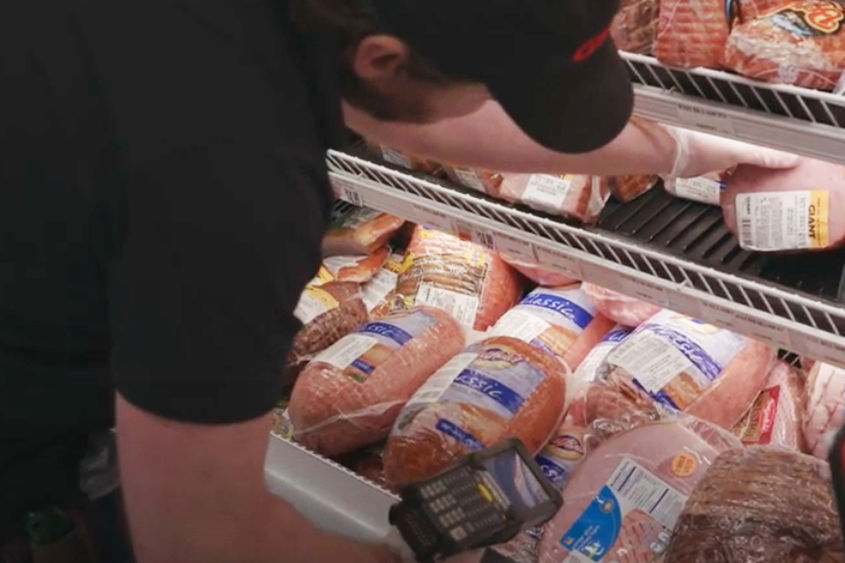 man filling meat case at grocery store