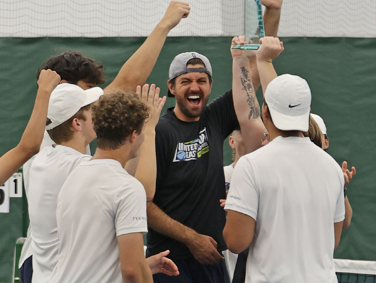 A group of men hold a trophy in the air and celebrate