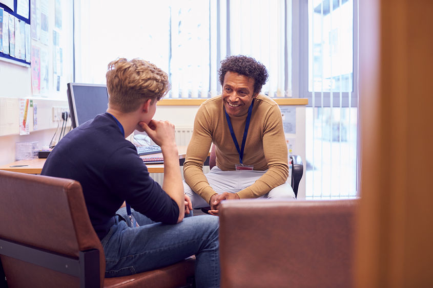 mentor has a conversation in office with student