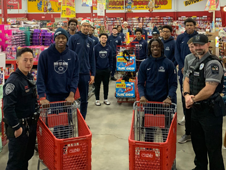 two police officers and several men's basketball players pose with carts in a store