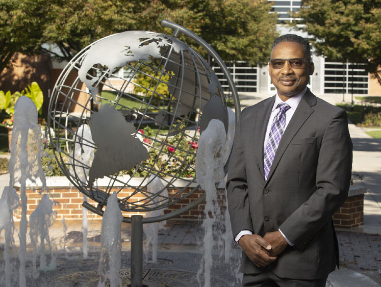 Professor Roderick Lee stands near globe fountain at Penn State Harrisburg