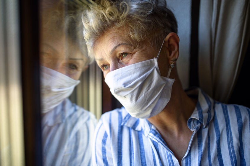 woman in mask looking out window